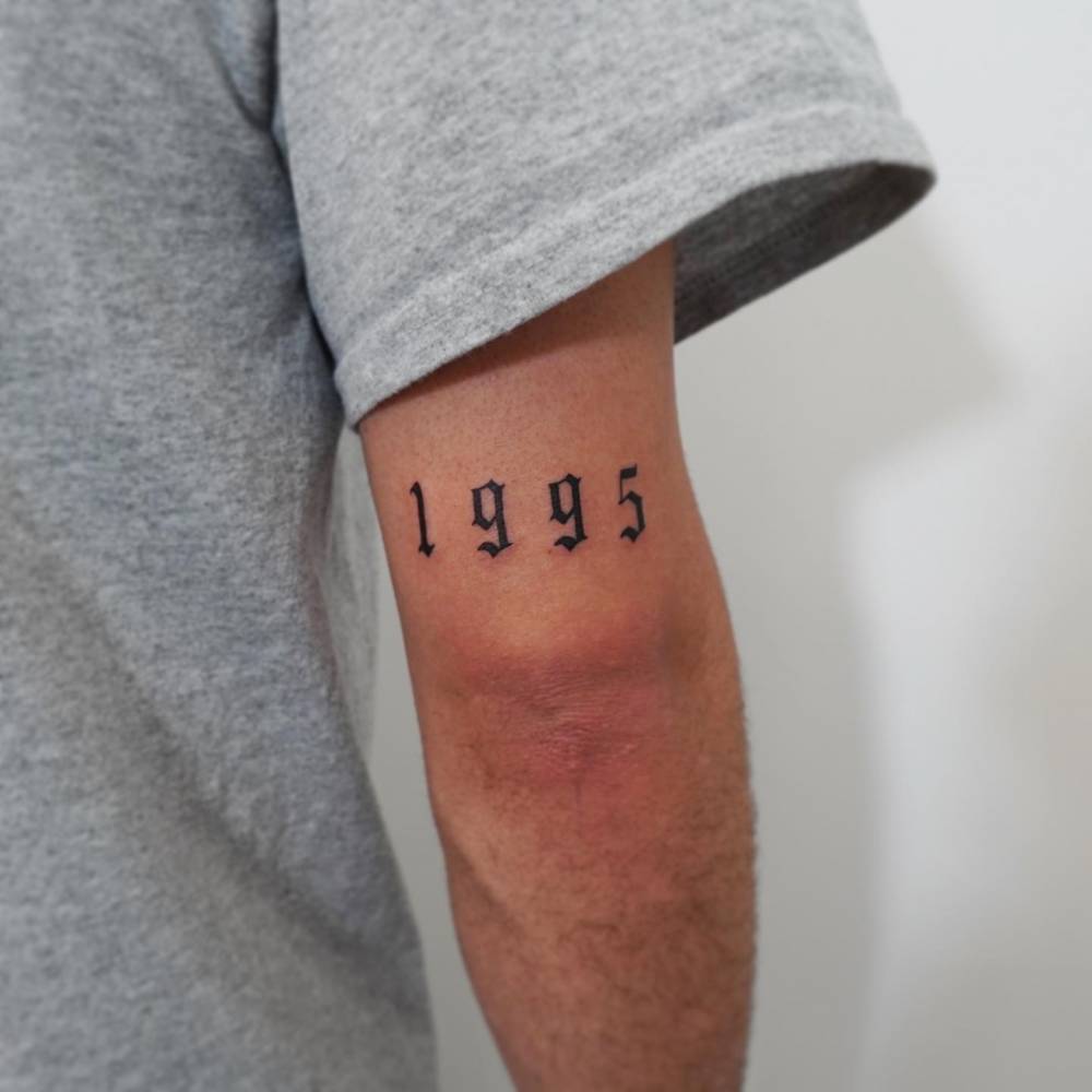 "1995" lettering tattoo located on the tricep.