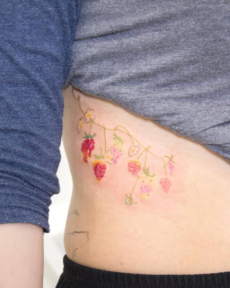 Watercolor style strawberries tattoo located on the rib.