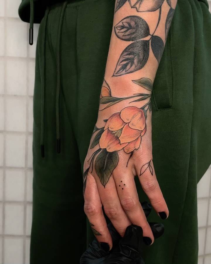 Illustrative style flower tattoo located on the hand.