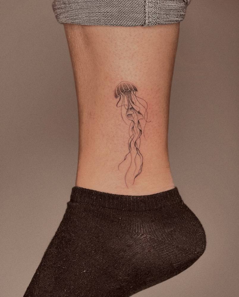 Jellyfish tattoo in illustrative style placed on the ankle.