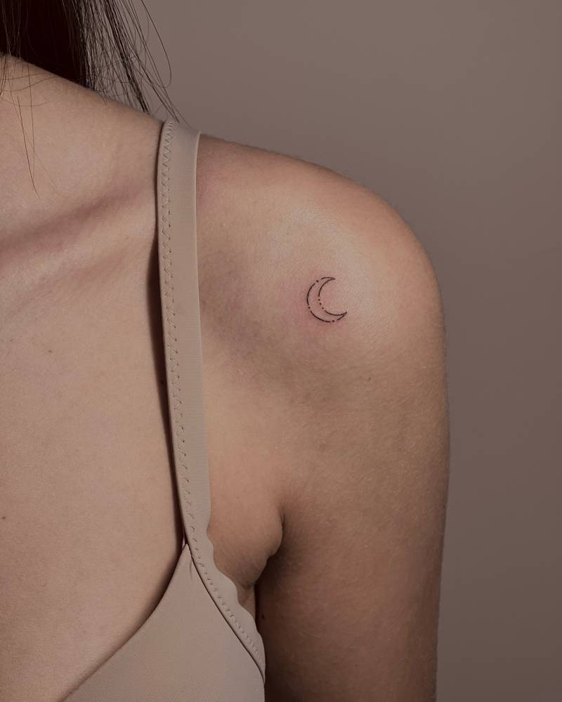Minimalistic style crescent moon tattoo located on the shoulder.