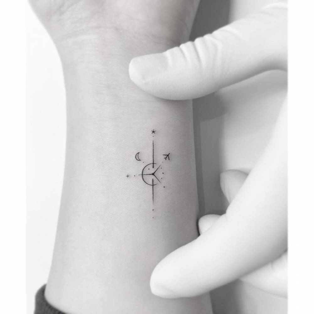 Compass rose tattoo in minimalistic style located on the wrist.