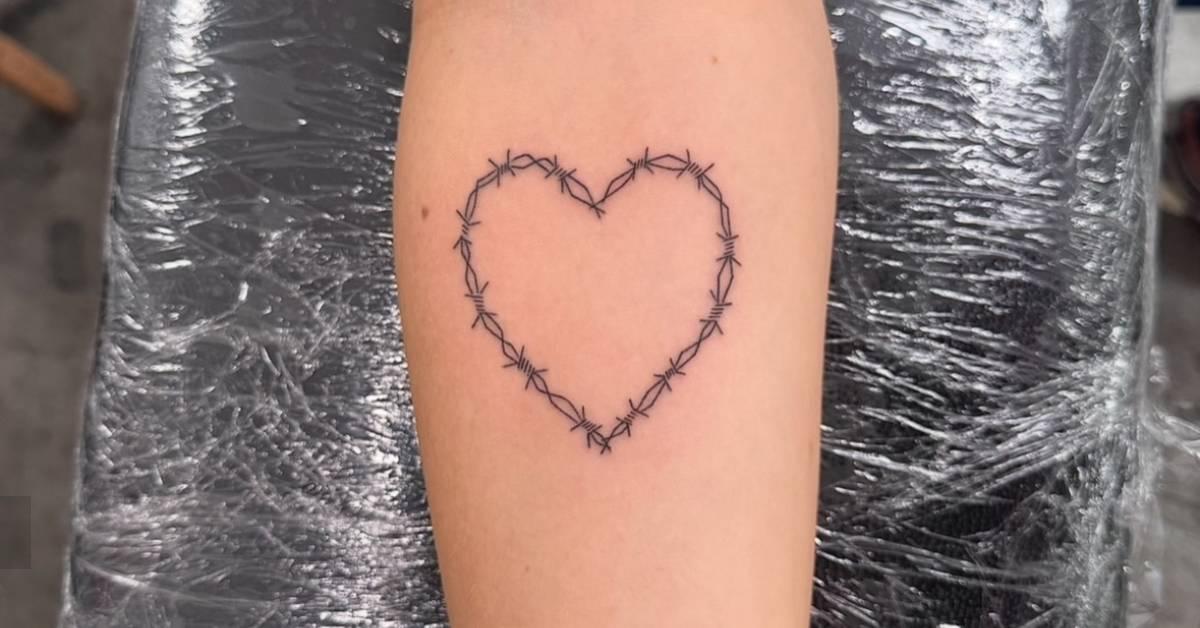 Fine line style barbed wire heart tattoo located on the