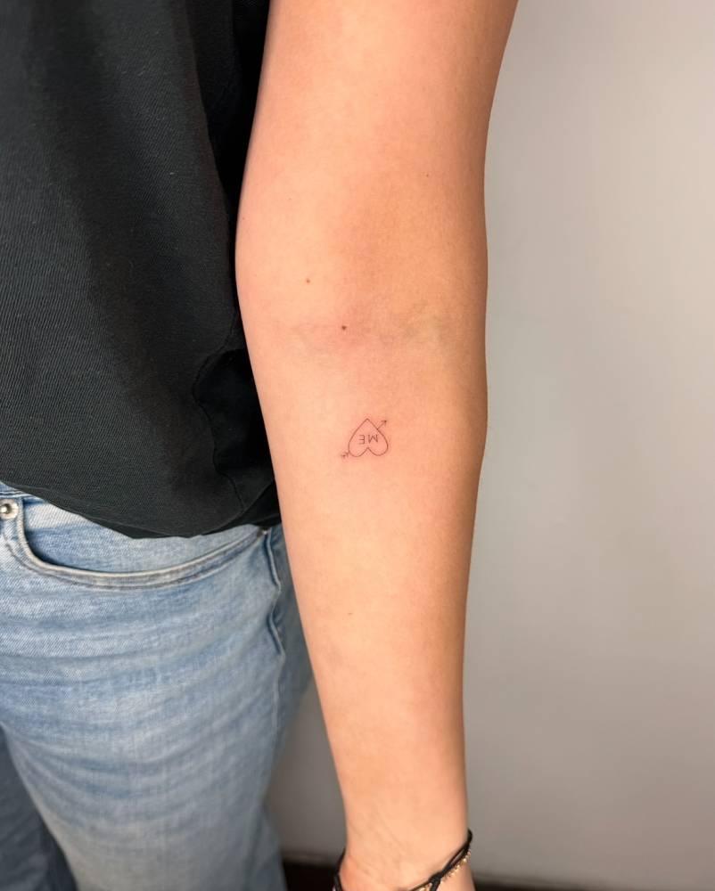 Heart and arrow with the word "me" tattoo located on the inner forearm.