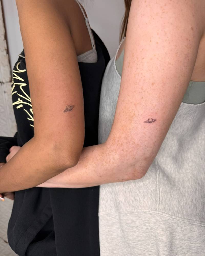Matching single needle Saturn tattoo for couple.