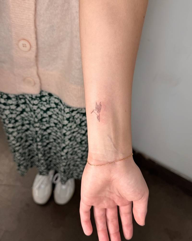Little tattoo of a hummingbird in fine line style placed on the wrist.