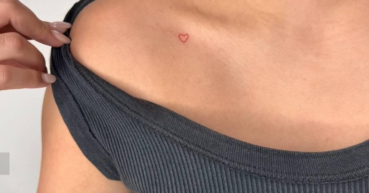 Tiny minimalistic red heart tattoo placed on the
