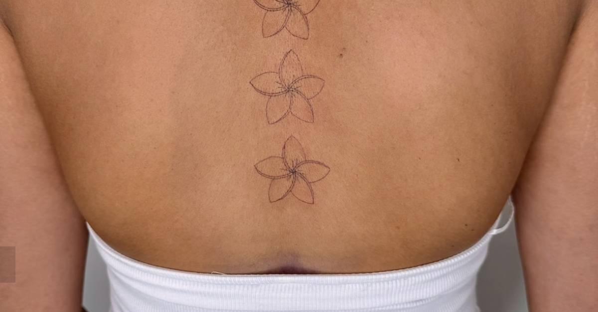 Plumeria flowers tattooed on the spine, done in fine