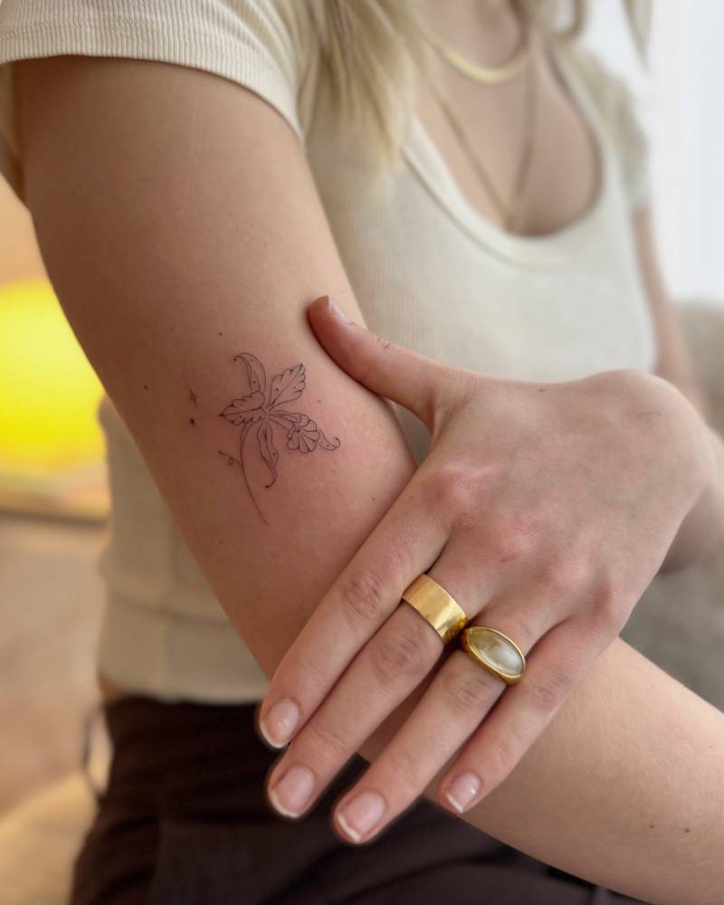Flower tattoo in fine line style located on the upper arm.