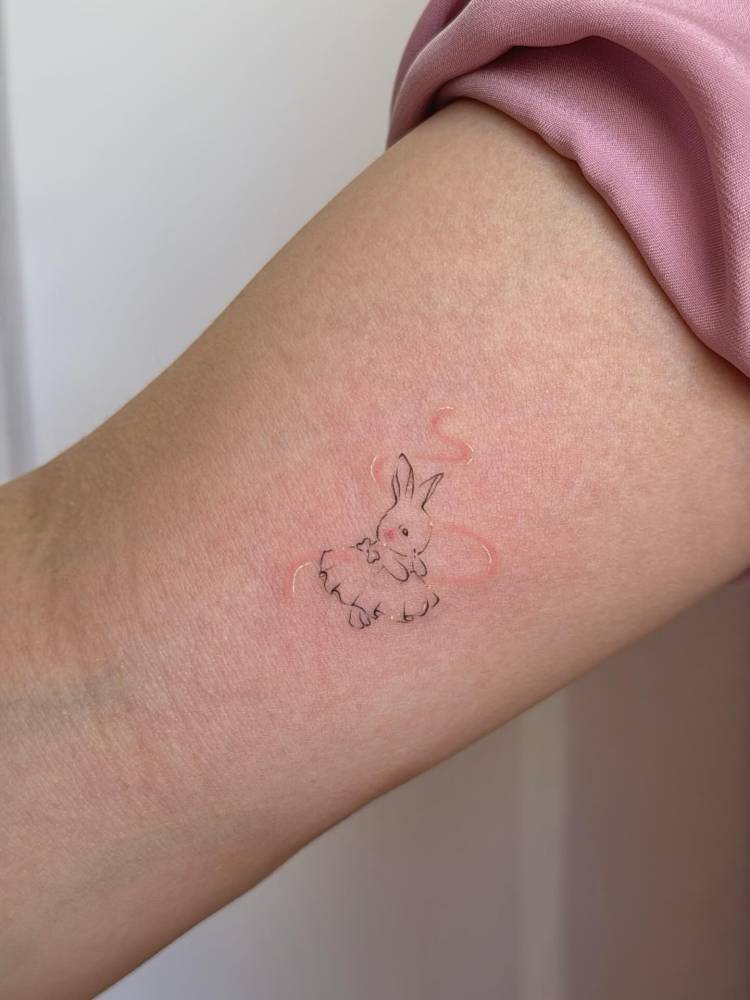 Fine line style ballet dancing rabbit tattoo located on the inner arm.