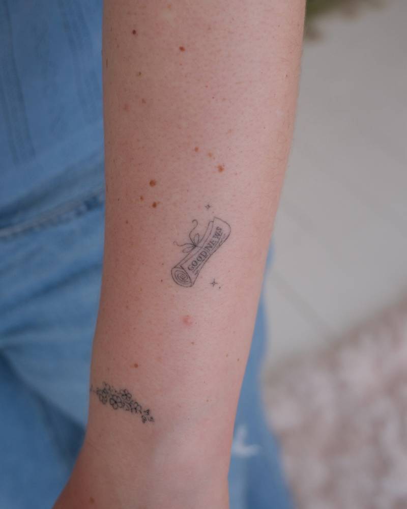 Newspaper tattoo in fine line style located on the forearm.