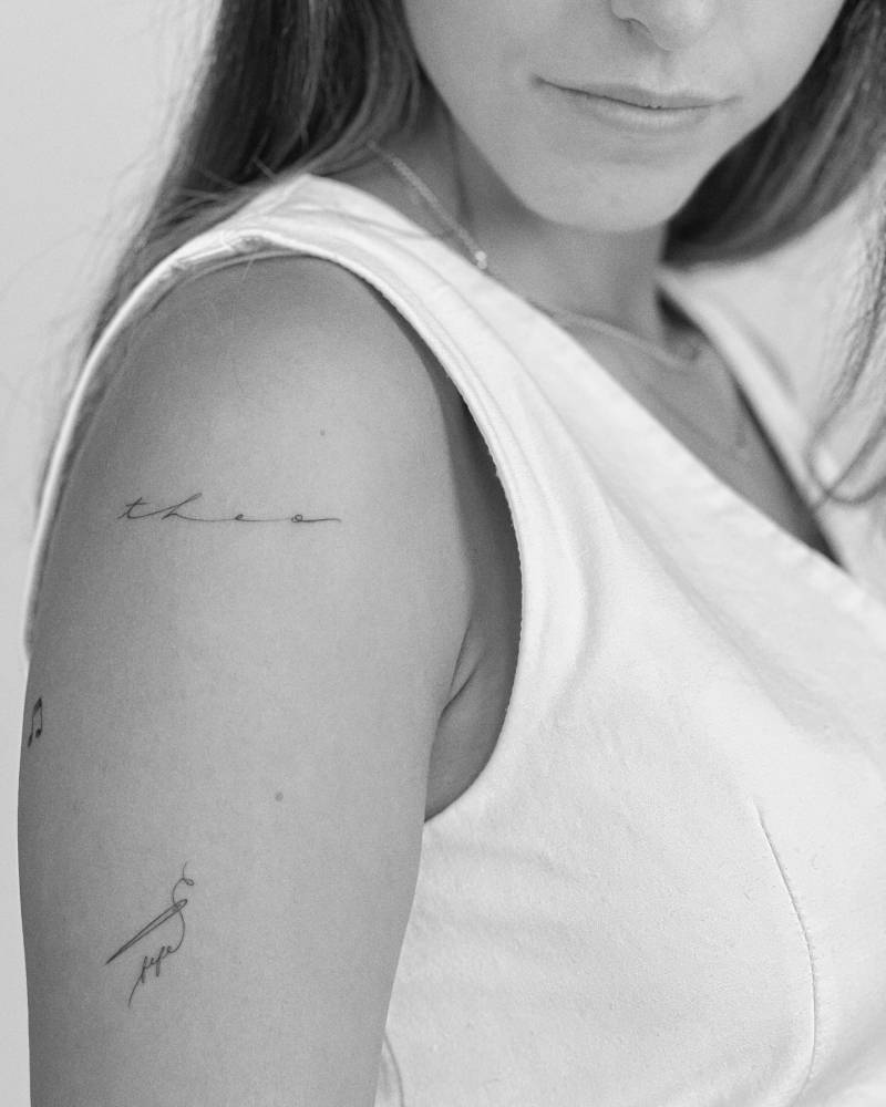 Fine line style needle tattoo located on the upper arm.