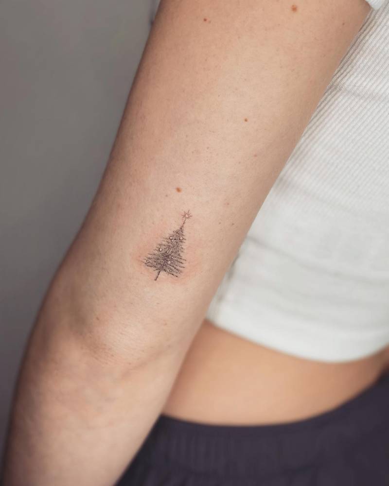 Micro-realistic style Christmas tree tattoo located on the tricep.