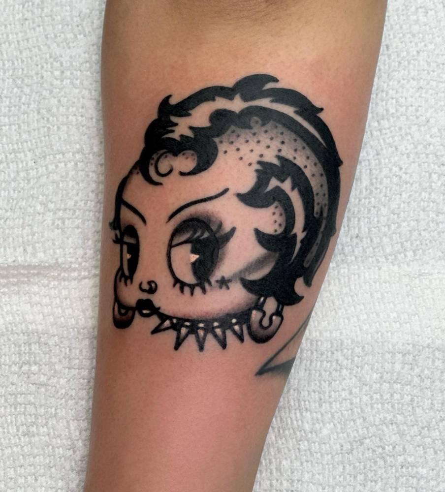 Punk Betty Boop portrait tattoo located on the inner forearm.