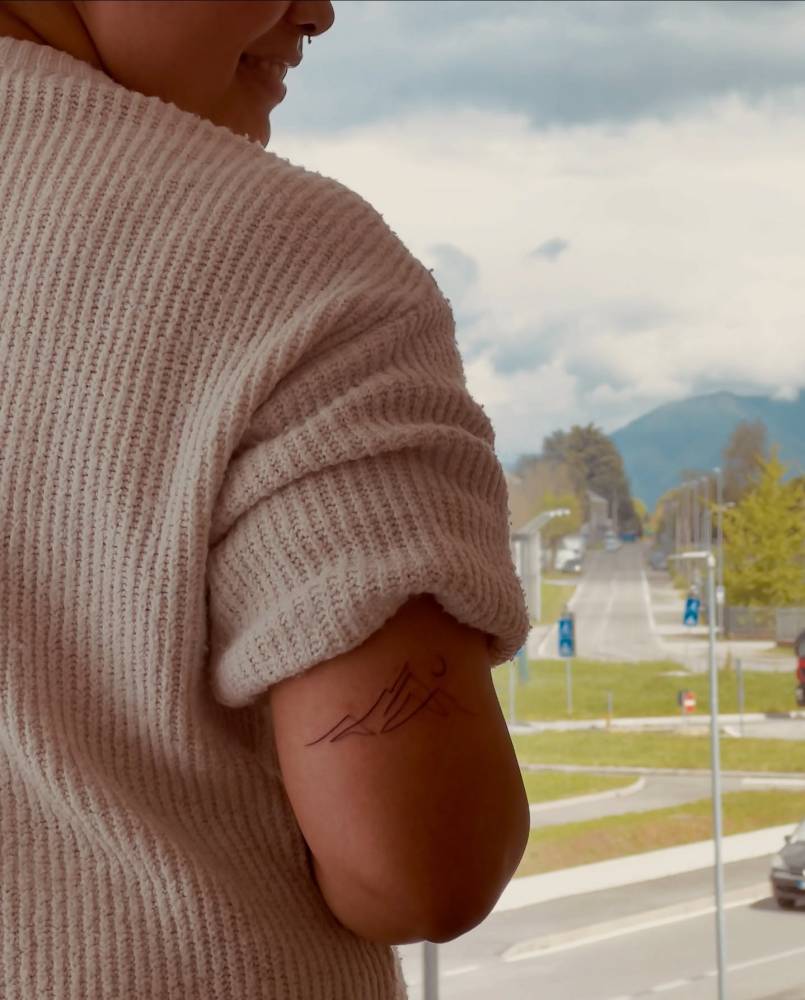 One line mountain tattoo located on the tricep.