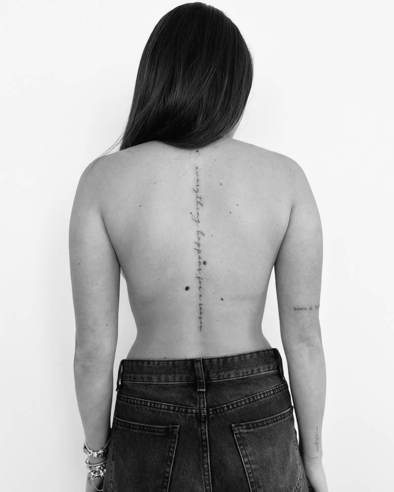 "Everything happens for a reason" lettering tattoo located on the spine.