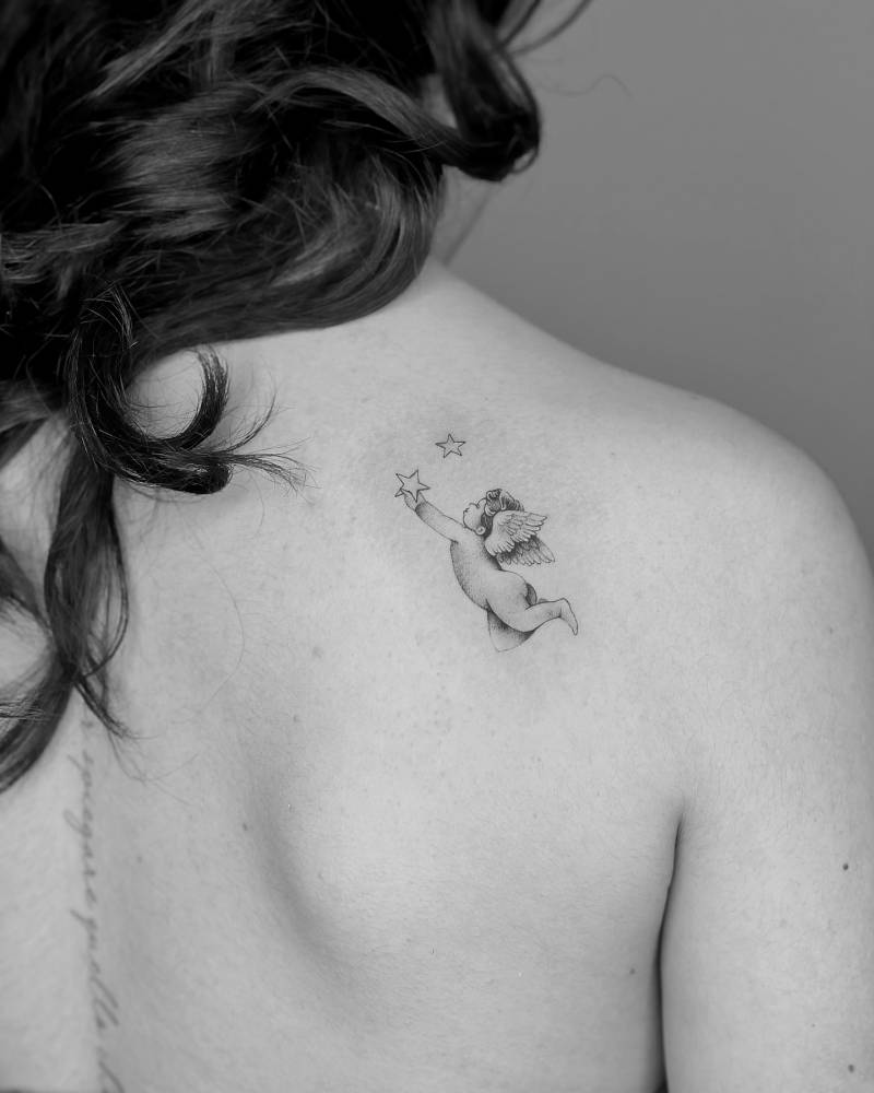 Little cherub tattoo in classical style located on the shoulder blade.