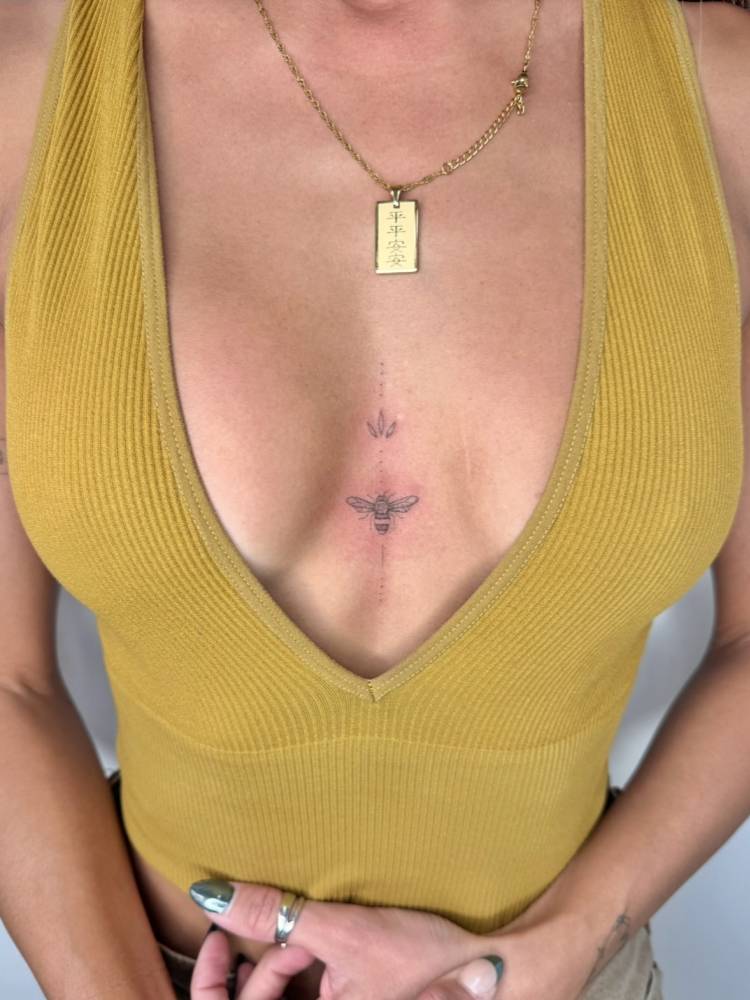 Single needle ornament and bee tattoo located on the sternum.