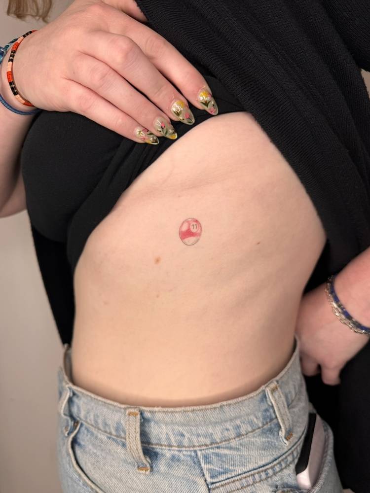 Healed billiard ball tattoo located on the rib.