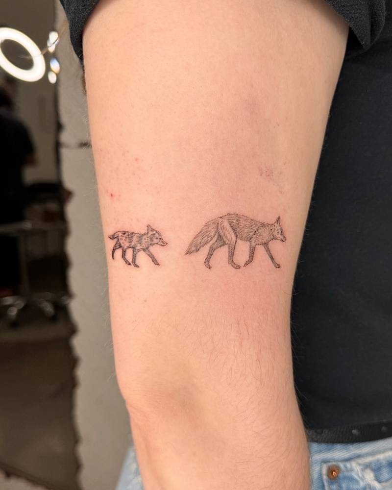 Illustrative style foxes tattooed on the upper arm.