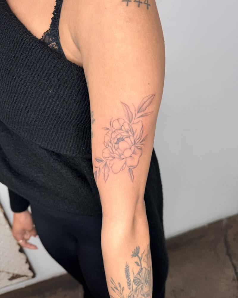 Peony tattoo in illustrative style located on the upper arm.