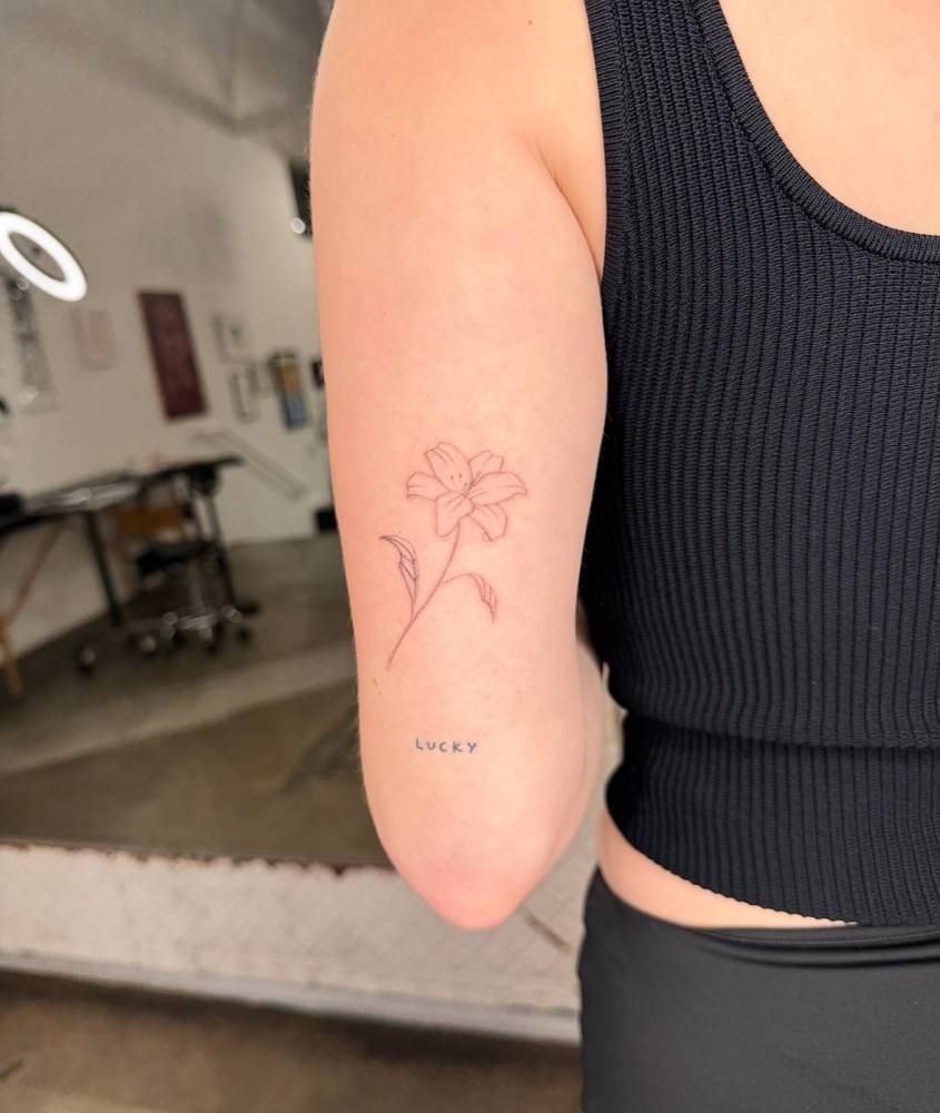 Single needle lily flower tattoo located on the tricep.