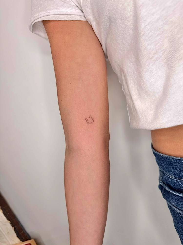 Tiny minimalistic horseshoe tattoo located on the inner arm.