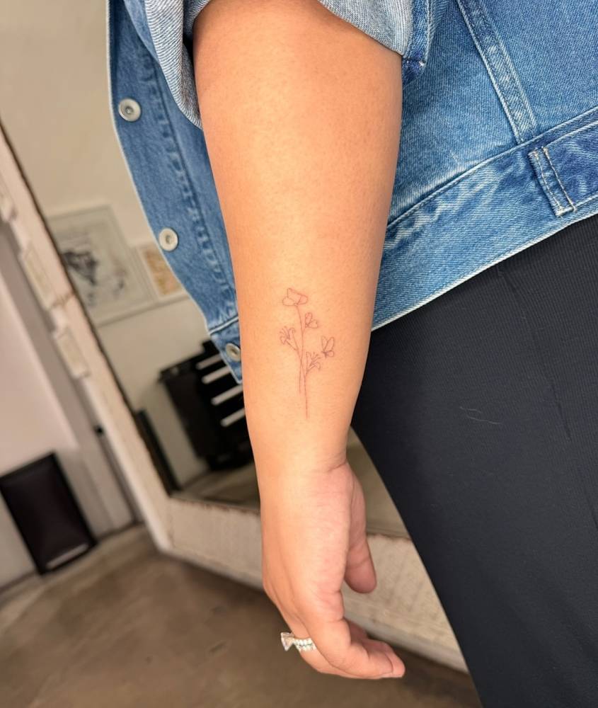 Single needle lily flowers and butterfly tattoo located on the wrist.