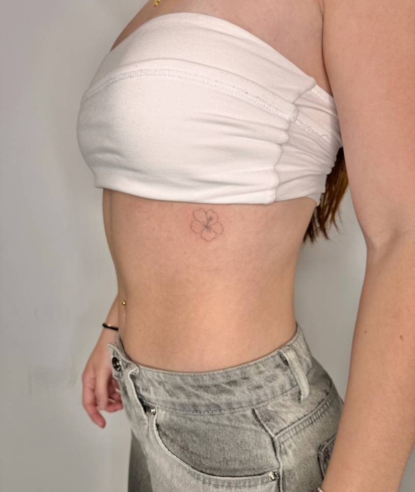 Hibiscus flower tattoo in fine line style located on the rib.