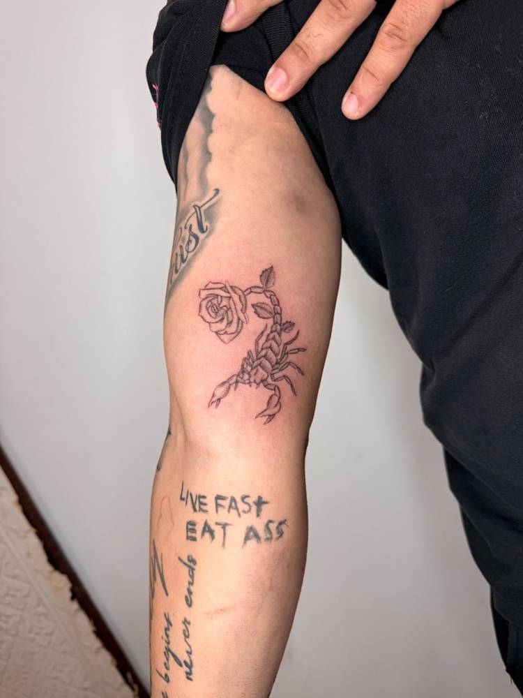 Illustrative style scorpion and rose tattoo located on the inner arm.