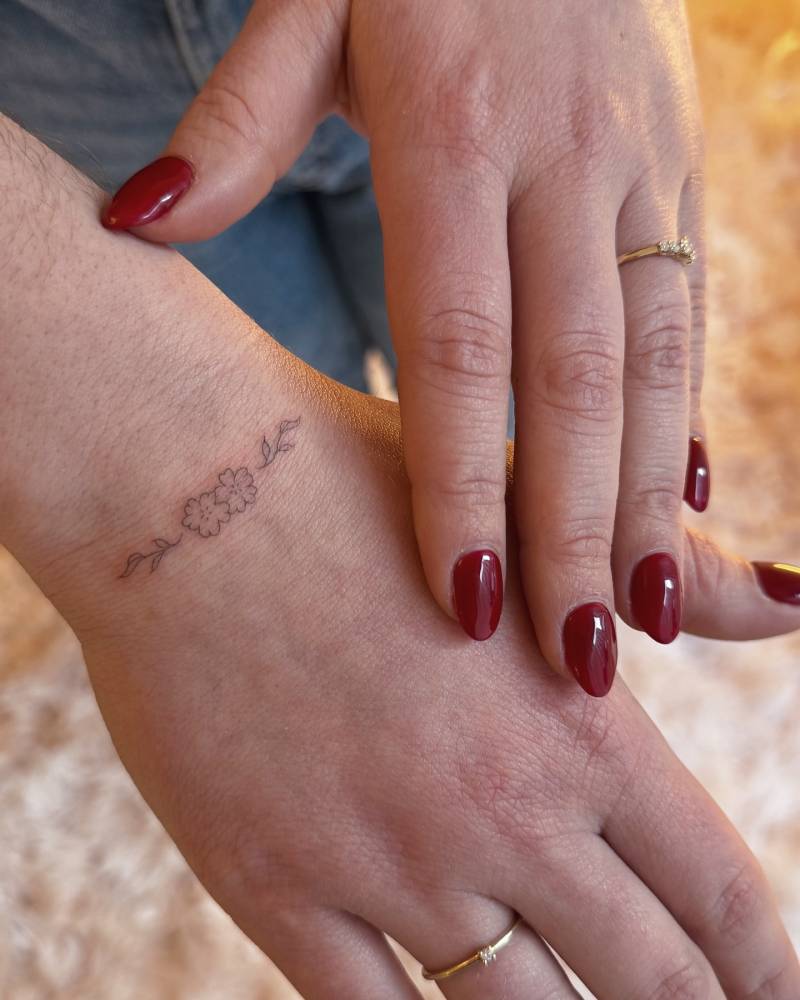 Little flowers tattoo in fine line style placed on the wrist.