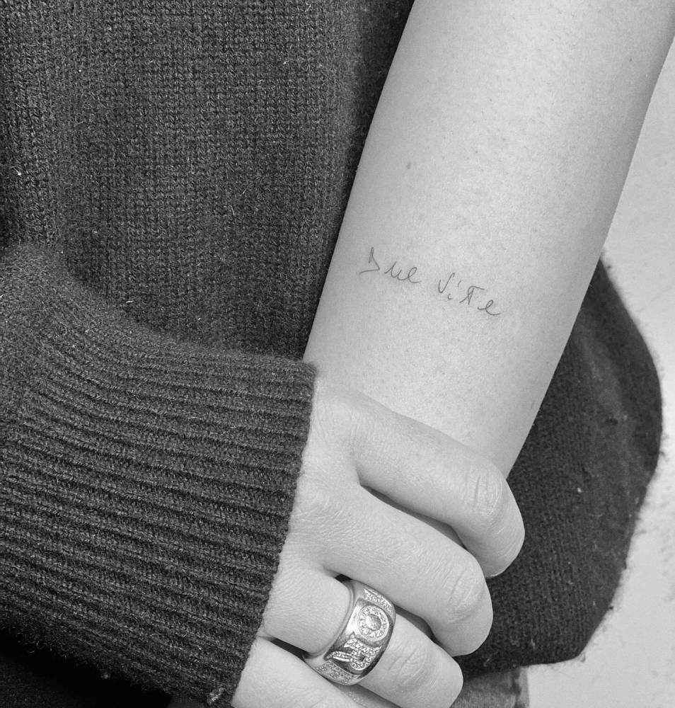 "Due vite" handwritten lettering tattoo located on the forearm.