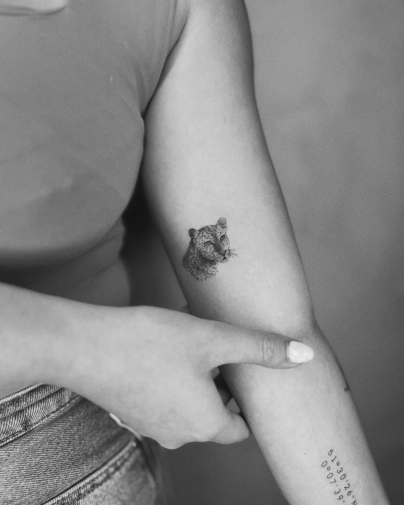 Micro-realistic style leopard portrait tattoo located on the inner arm.