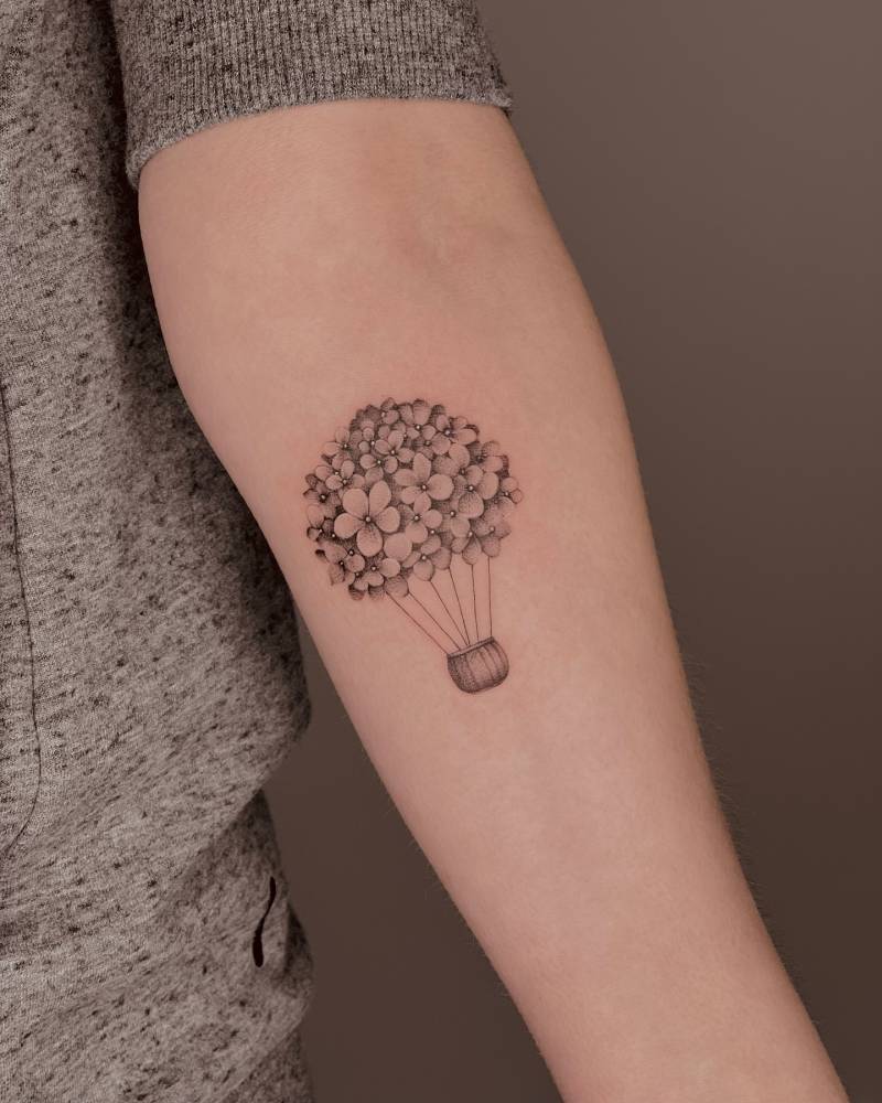 Micro-realistic style hydrangea balloon tattoo placed on the inner forearm.