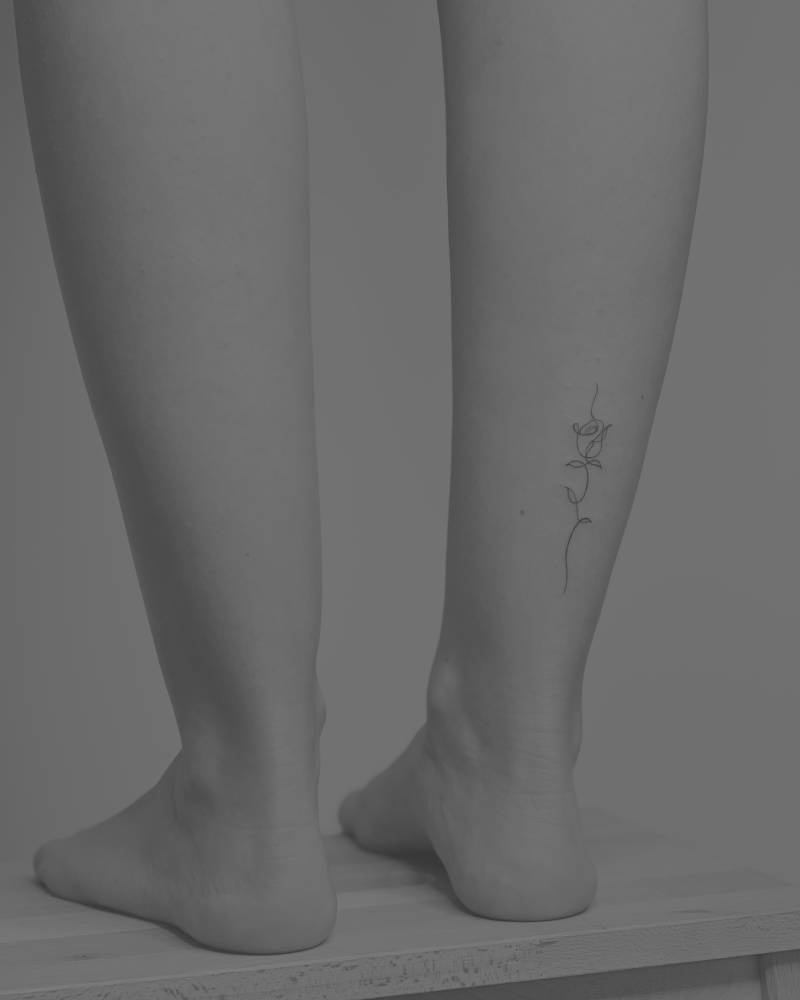 One line rose tattoo located on the achilles.
