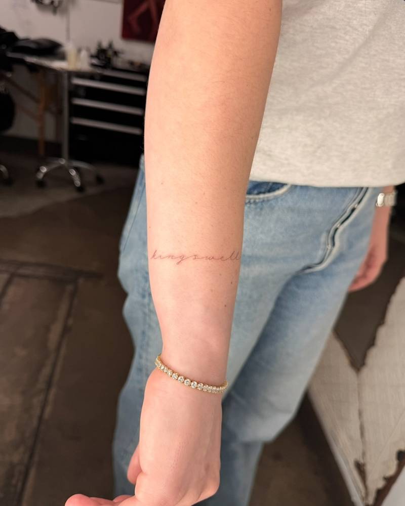 "Kingswell" handwritten lettering tattoo placed on the wrist.