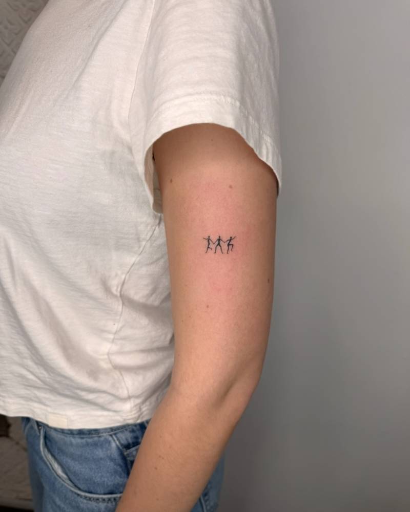Tiny minimalistic dancers tattooed on the upper arm.