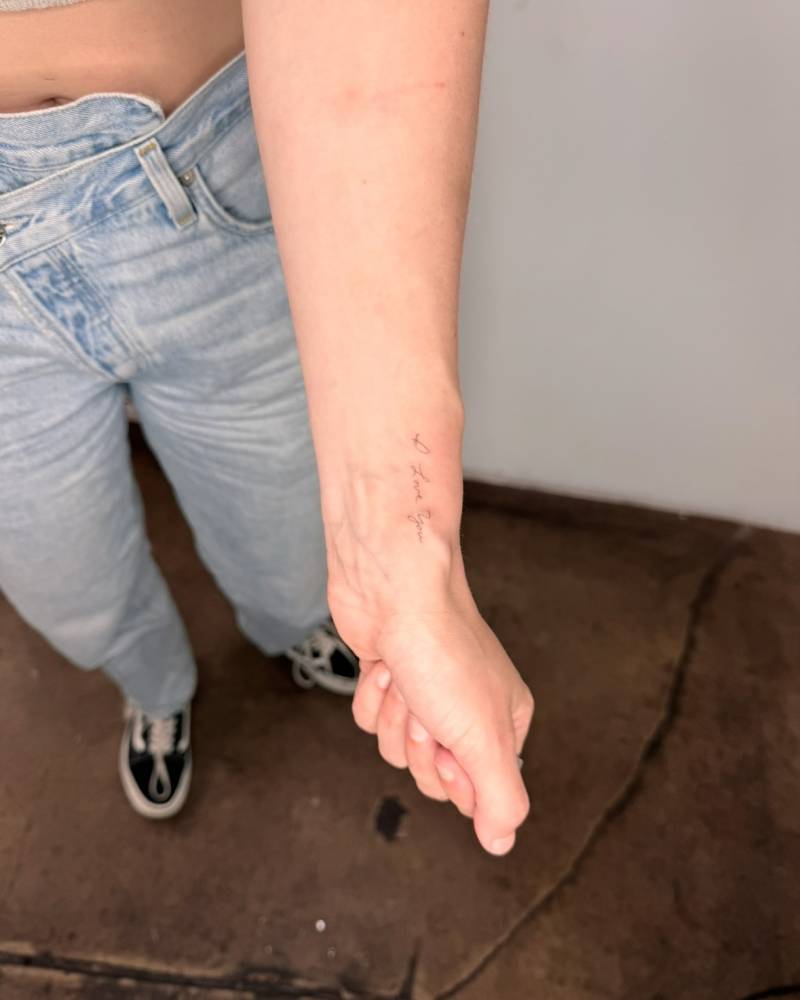 Handwritten font "I love you" lettering tattoo placed on the wrist.