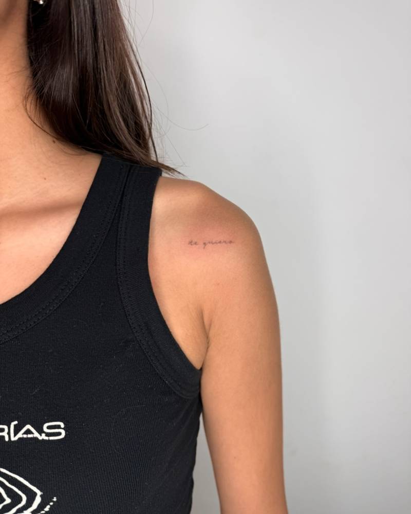 Handwritten font "te quiero" lettering tattoo located on the shoulder.