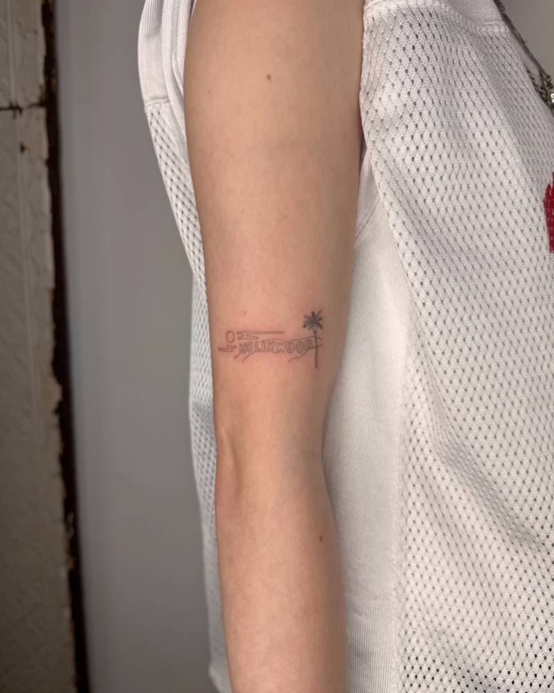 Single needle Hollywood Sign tattoo located on the upper arm.