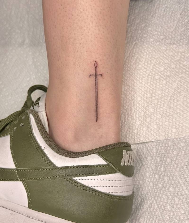 Little single needle sword tattoo located on the ankle.