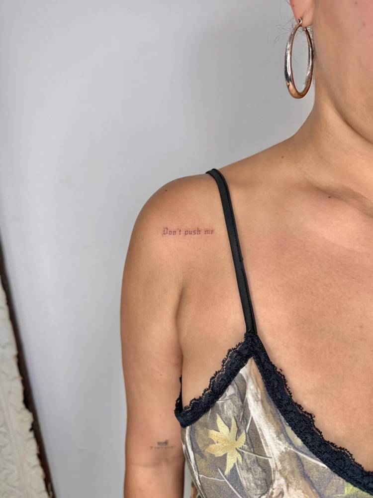 "Don't push me" lettering tattoo in gothic font located on the shoulder.