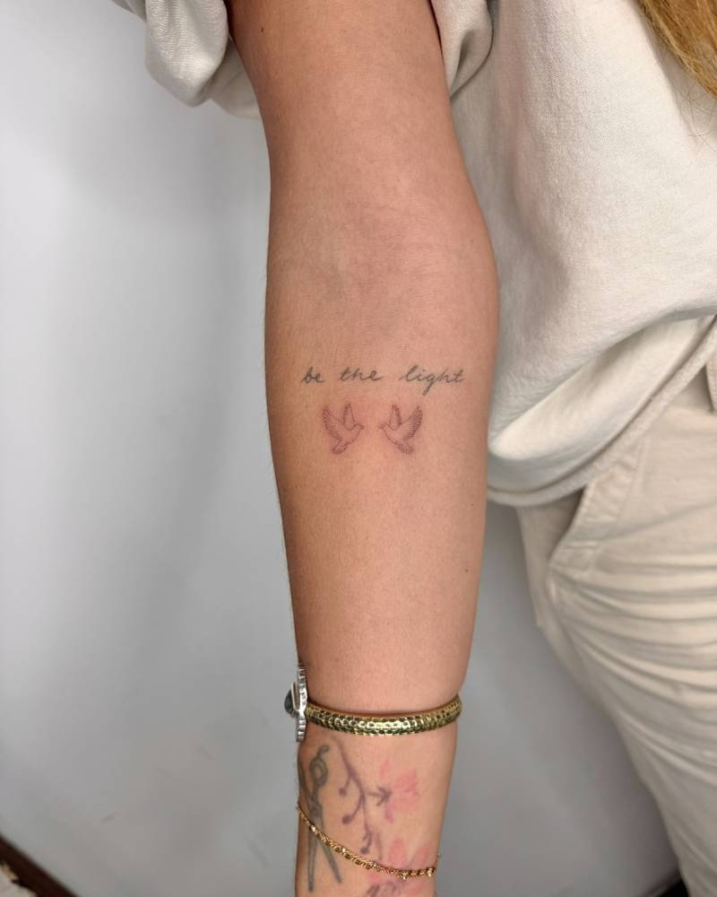 Flying doves tattoo in fine line style located on the inner forearm.