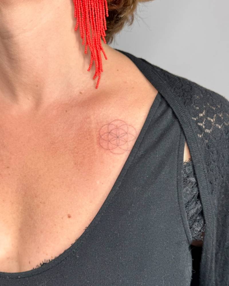Single needle flower of life tattoo located on the collarbone.
