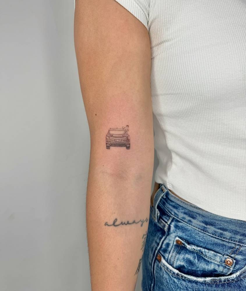 Little car tattoo located on the bicep, illustrative style.