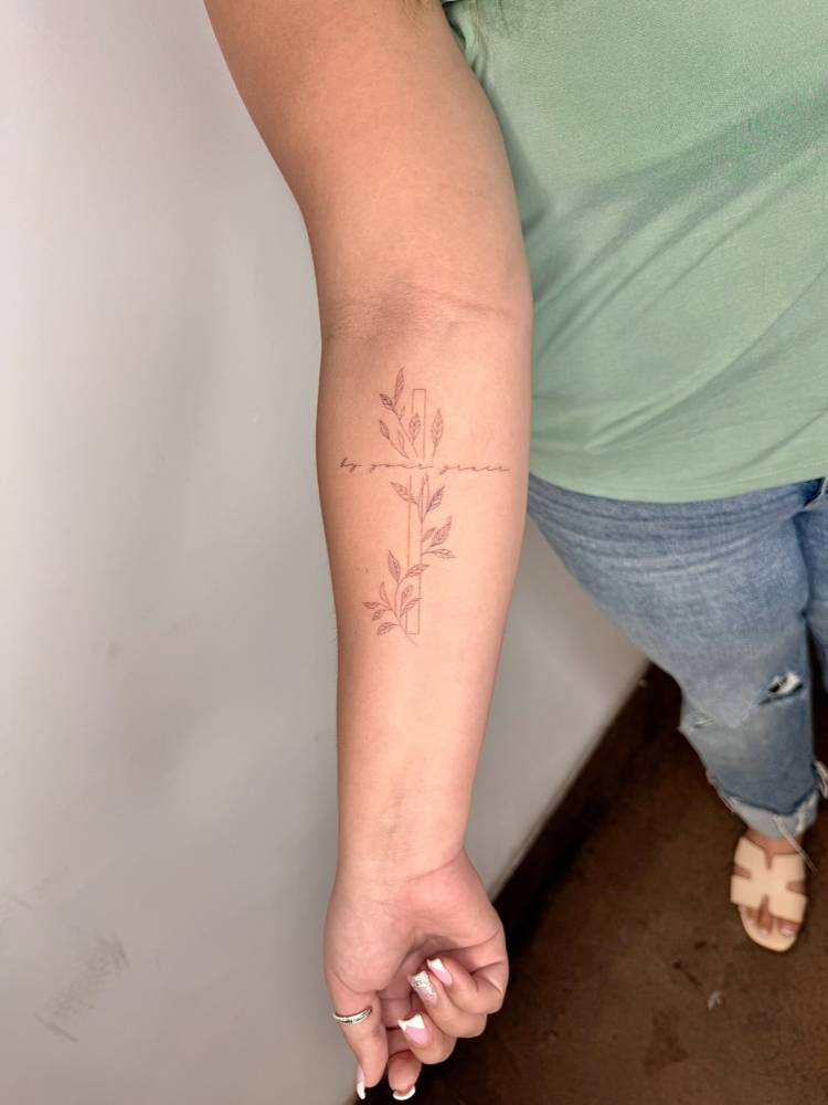 "By your grace" and leaves tattoo done on the inner forearm.