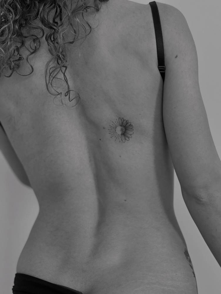 Daisy flower and sun tattoo located on the back, illustrative style.