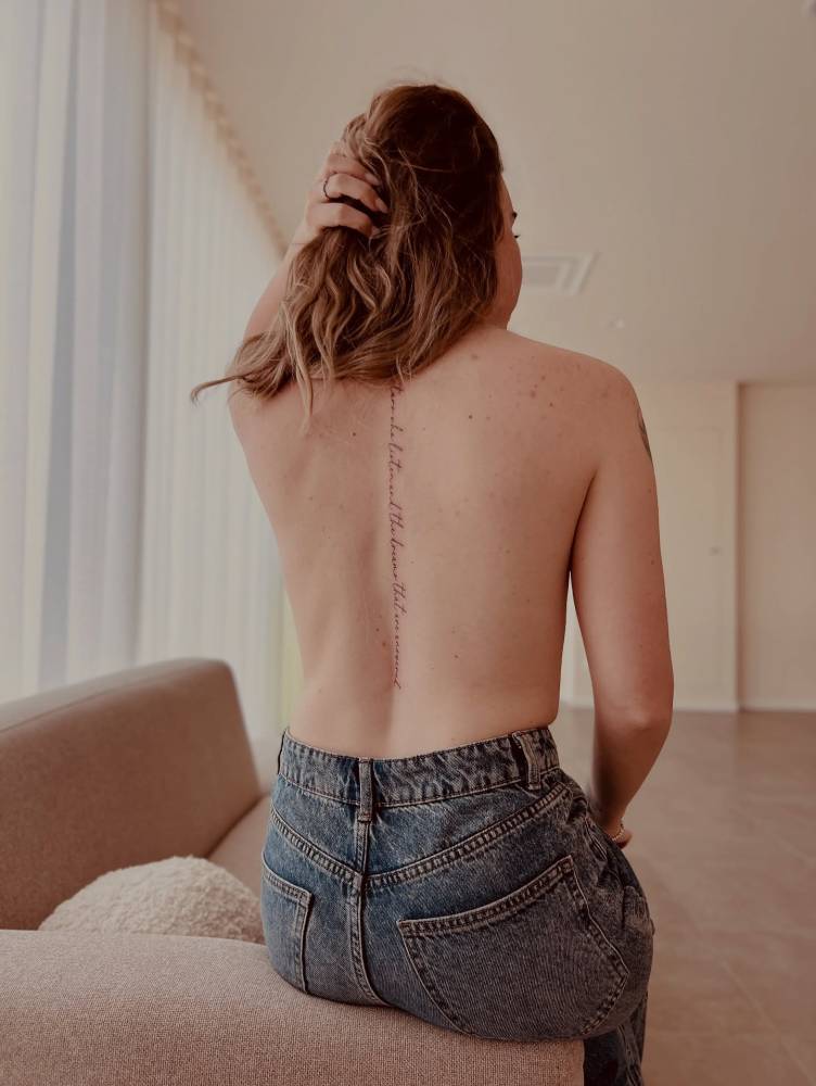Handwritten lettering tattoo placed on the spine.