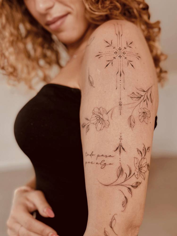 Flowers and ornaments tattooed on the upper arm, illustrative style.