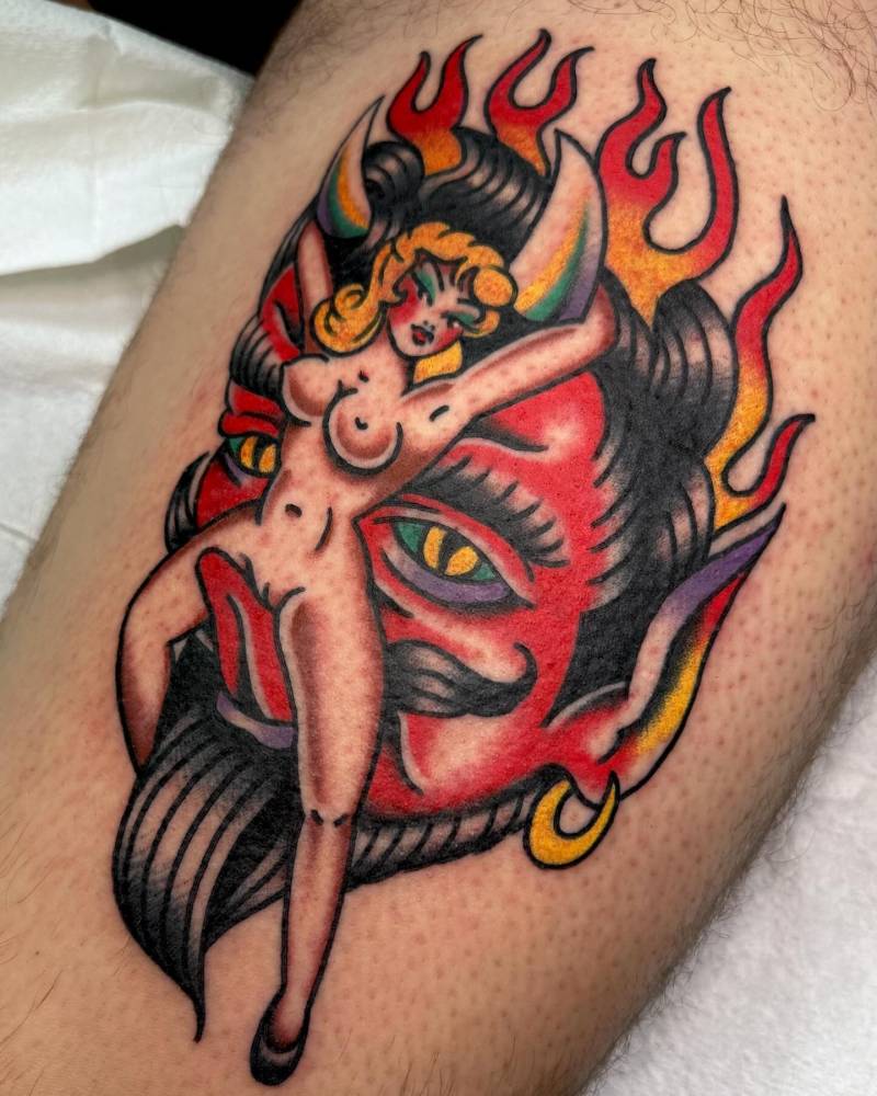 Traditional style devil and nude woman tattoo located on the thigh.